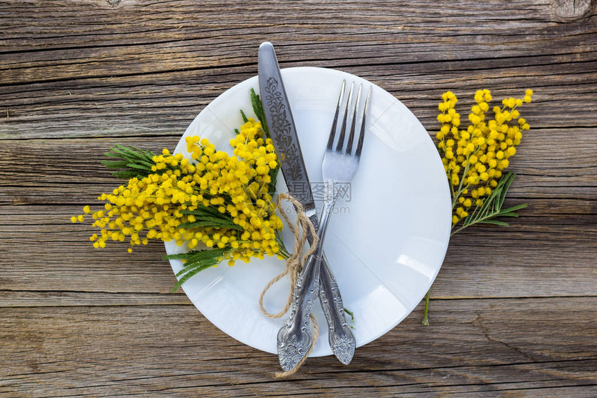 带盘子的叉刀和木桌上的米莫萨花用于春图片