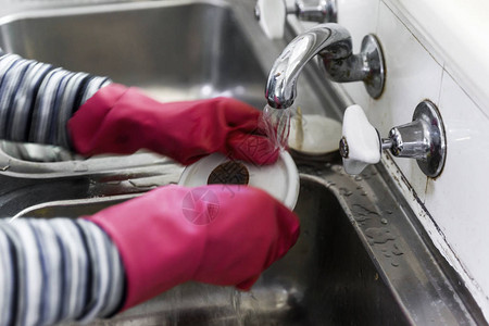 妇女手上戴着粉红色手套洗碗图片