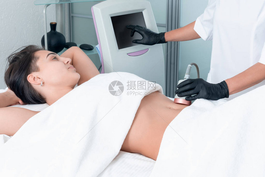 超声空化塑身治疗女人在美容院的腿上接受抗脂肪图片