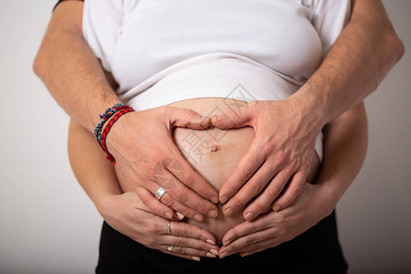 美丽的孕妇和她英俊的丈夫抱着肚子的刻画图片