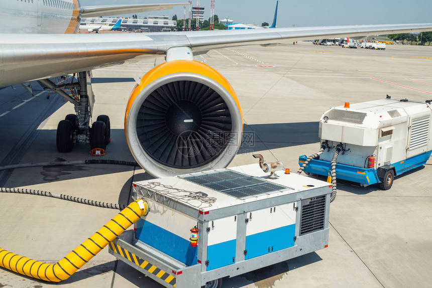 大型现代商用飞机停在机场跑道上并连接到地面电源装置图片