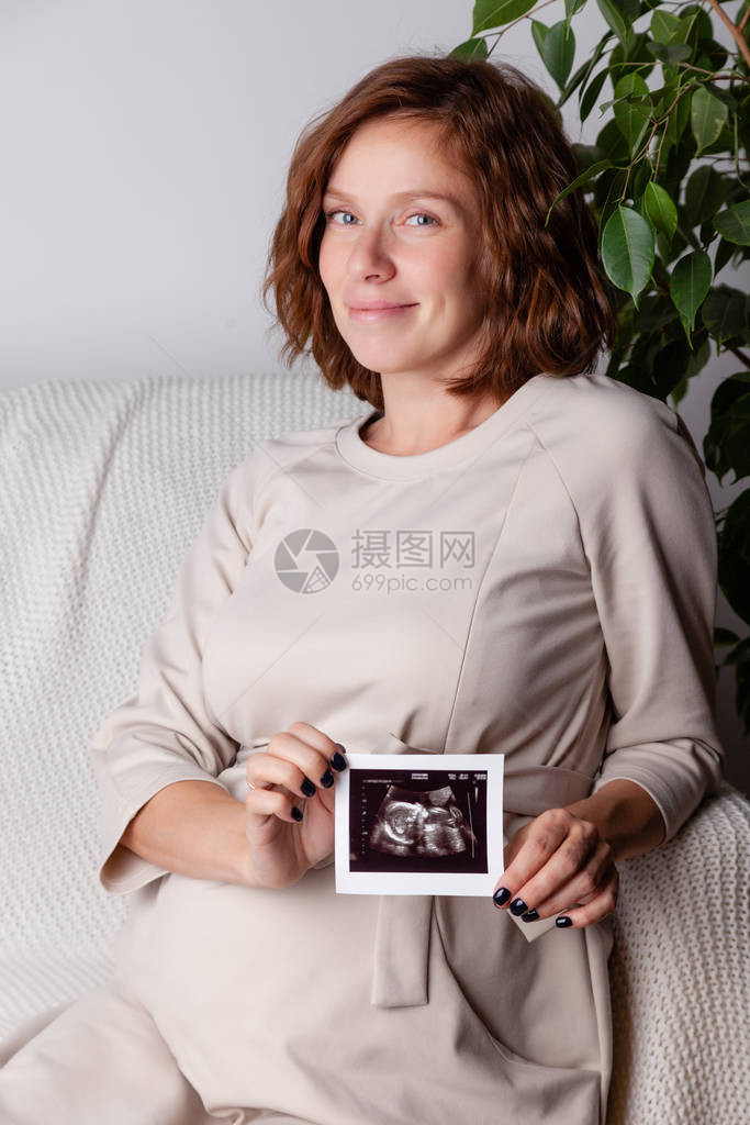 美丽的孕妇拿着超声图像的画像怀孕保健妇科医学的概念等待婴儿的年轻母亲特写镜头图片