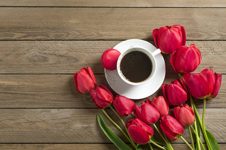 一排红色郁金香和一杯黑咖啡美式咖啡在木制背景上图片