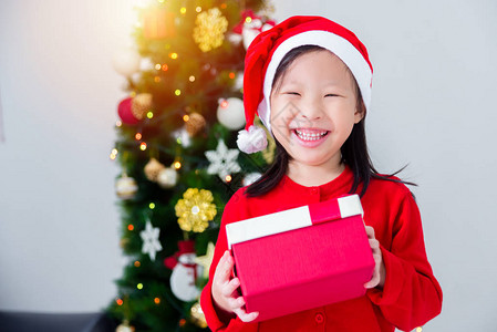 穿着圣达克萨斯帽子的亚洲小女孩在圣诞树前拿着装图片