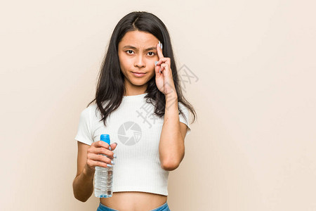 年轻女拿着水瓶指着图片