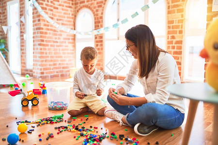 美的老师和幼稚园儿童在幼儿园玩许多玩具的图片