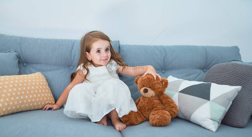 坐在沙发上坐在家里玩泰迪熊图片