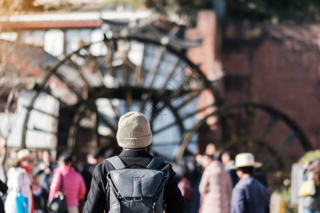 年轻的旅行者在丽江古城的巨型水轮上旅行图片