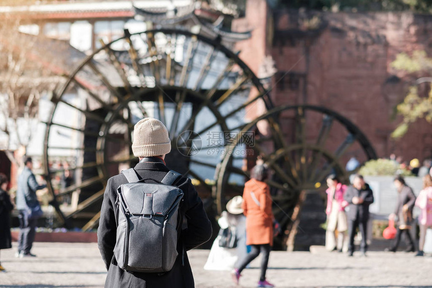 年轻的旅行者在丽江古城的巨型水轮上旅行图片