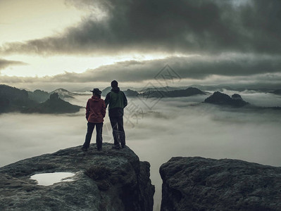 徒步旅行者女人和男人穿着深色运动服在最高的山上图片