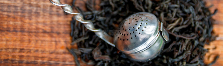 老式过滤器的横幅与木制背景上的红茶干叶茶概念茶叶图片