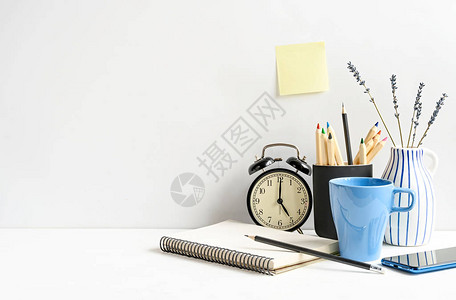 工作场所与记事本电话铅笔咖啡时钟和白墙上的白桌上的空白粘纸图片