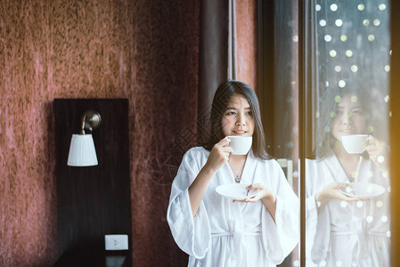 美丽的亚洲女人早上醒来后在卧室喝热咖啡图片
