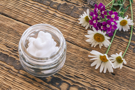 玻璃罐里的化妆品奶油木板上的花束和香菊图片