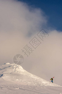 滑雪者徒步攀登一座积雪覆盖的山峰图片
