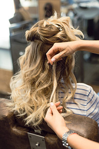 美发师在金发女郎身上制作卷发和卷发美发师的手图片