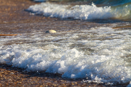 海浪与海边的白色泡沫温暖的大海的夏天海滩海岸由贝壳和沙子组成图片