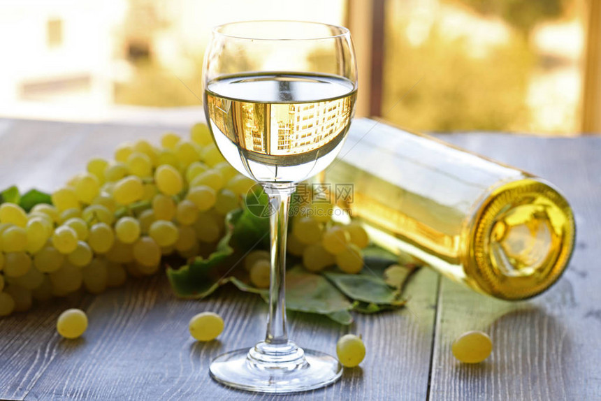 一杯葡萄酒和一串新鲜白葡萄的顶端景色在老木质图片