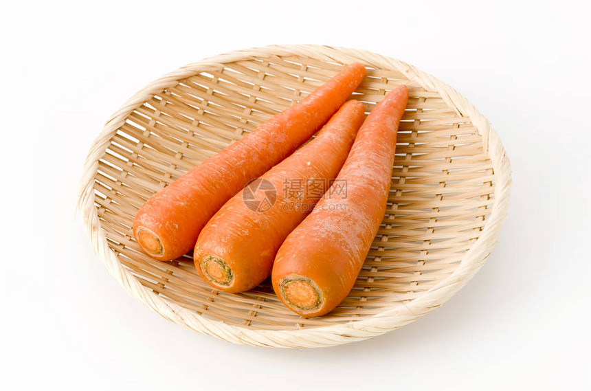 白色背景竹滤锅上的新鲜胡萝卜图片