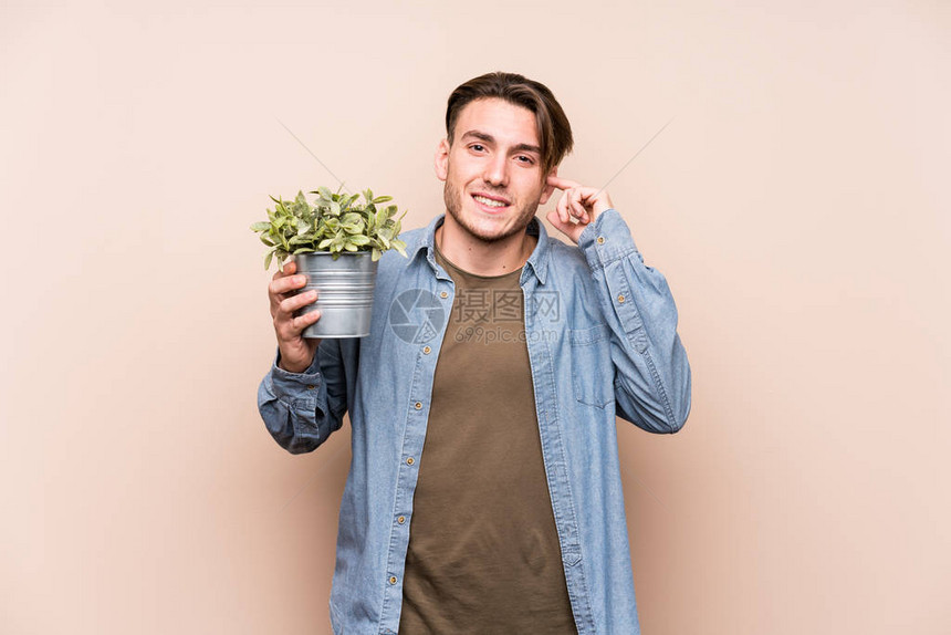 年轻的caucasian男子拿着植物图片