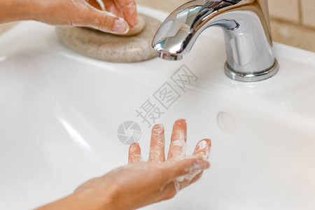 卫生概念用水在龙头下用肥皂洗手图片