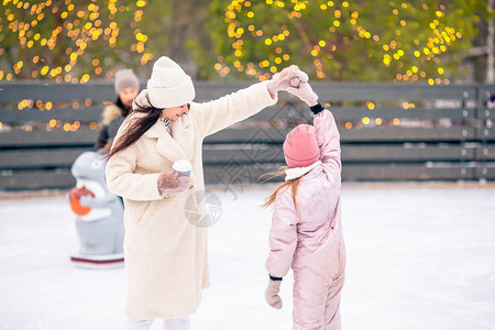 可爱的小可爱女孩和她妈在冰场滑冰背景图片