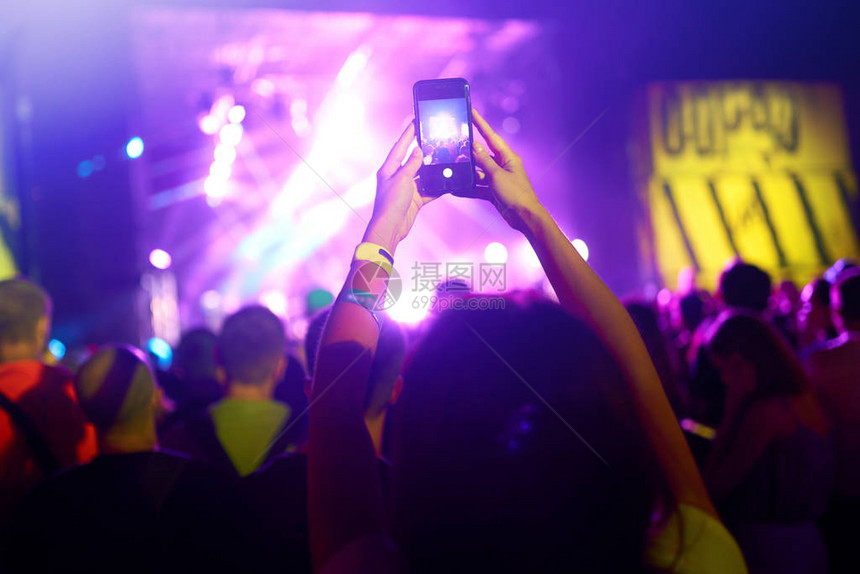 手拿着电话记录现场音乐节人们在公共音乐会期间用智能手机拍照举起手图片