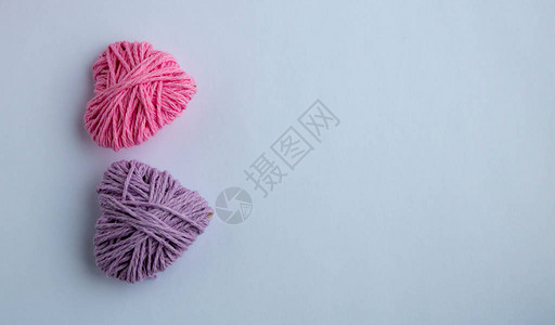 粉色和淡紫色针织纱心形情人节最小的概念贺卡与粉红色背景上的心顶视图平图片