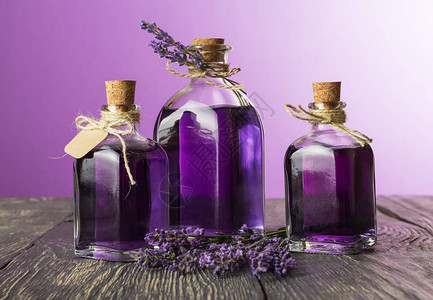 三瓶紫色背景上带有薰衣草和新鲜树枝的芬芳酊剂图片