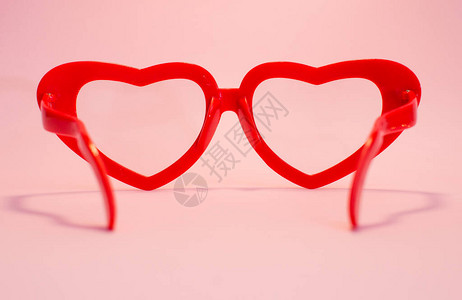 红眼镜在粉红色背景的红心上情人节女图片