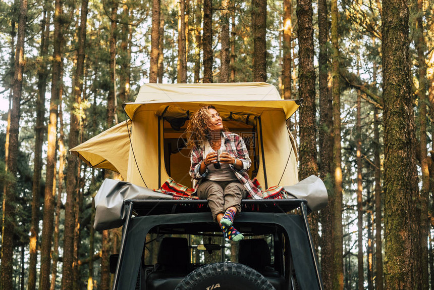 旅行和流浪生活方式概念与快乐孤独的成年女坐在屋顶帐篷汽车上图片