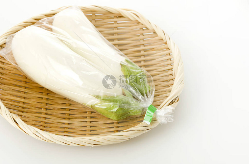白色背景竹滤器上塑料袋中的白茄子图片