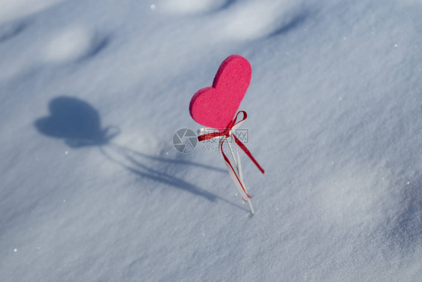 粉红的心在雪地上沾着白丝带和红图片