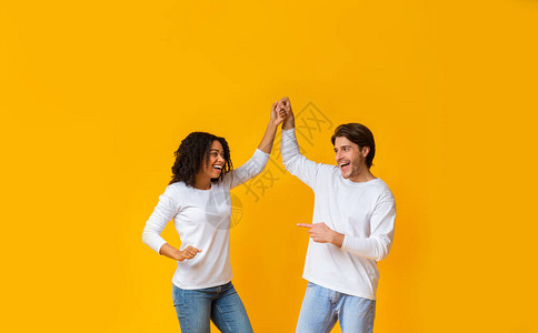 欢快的跨种族爱人一起玩游戏握手和在黄背景上跳舞自由空图片