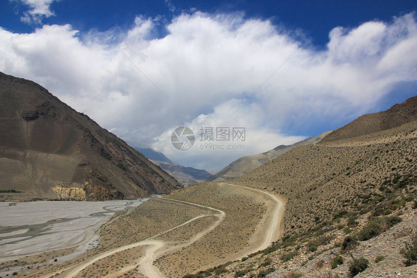 在蓝天和美丽的云彩背景的尼泊尔山区的土路图片