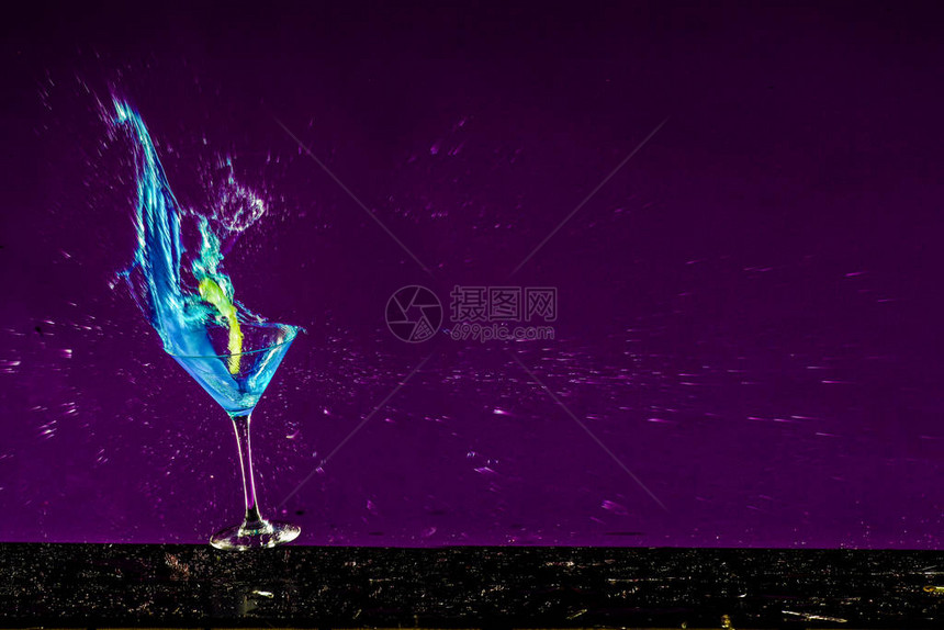 带有紫色背景和蓝色液体的破碎酒精玻璃的新年概念图片