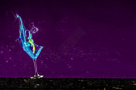 带有紫色背景和蓝色液体的破碎酒精玻璃的新年概念图片