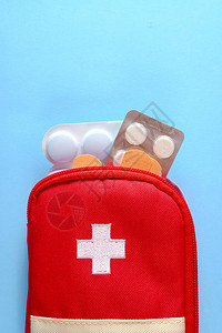 药丸和粘合绷带从开放的红色旅游急救箱中伸出来图片