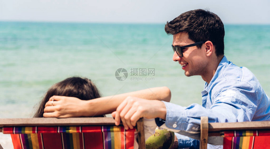 浪漫情侣年轻夫妇一起在热带海滩放松男人和坐在椅子上的女孩交谈夏假Summ图片