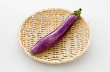 白色背景竹筛上长的浅紫色茄子高清图片