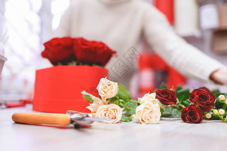 花店女人用红玫瑰制作盒子用鲜花制作帽子盒的过程图片