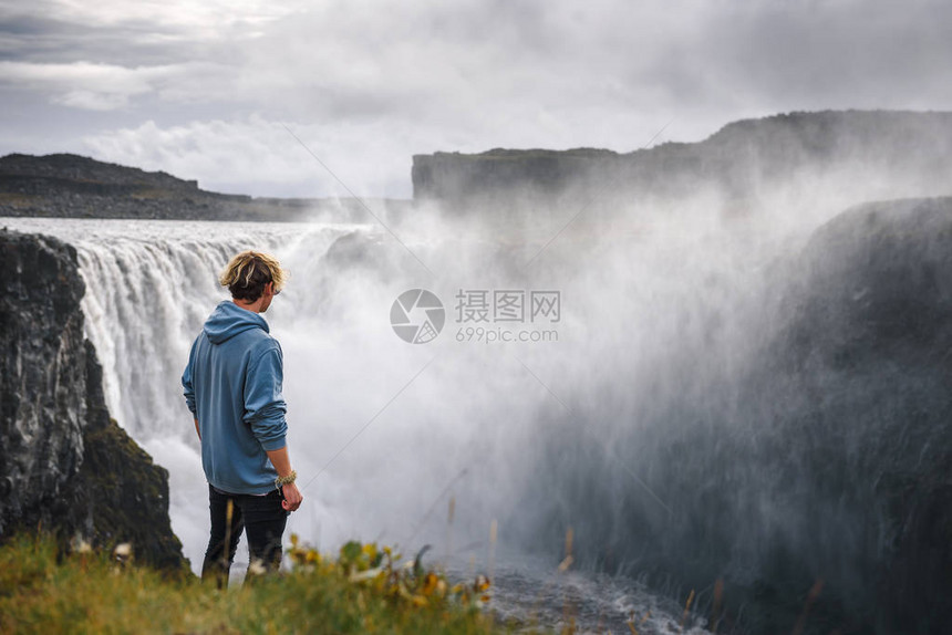 年轻的远足者站在位于冰岛弗约鲁姆河Jokulsa的Detifos瀑布边上图片