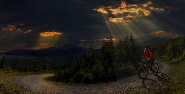 骑自行车的骑手在日落山区森林景观上骑车图片