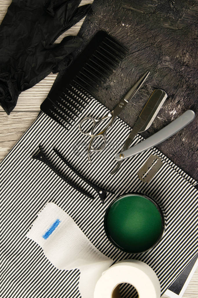将理发工具剪刀危险剃须刀片露水和绿色发胶放在一条漂亮的条纹毛图片