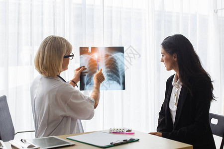 高级女医生和病人在医院检查X光报告在图片