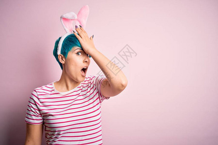 在粉红色的背景上戴着复活节兔子耳朵图片