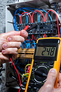 具有多米测试器的电工测量住宅配电池板的电压图片