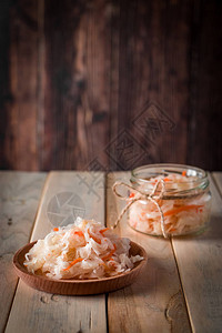 在深棕色背景的自制酸菜在木制背景的罐子里发酵的卷心菜生态食品图片