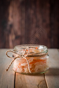 在深棕色背景的自制酸菜在木制背景的罐子里发酵的卷心菜生态食品图片