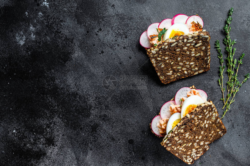 三明治配热熏鲑鱼和谷物面包鳟鱼黑色背景图片